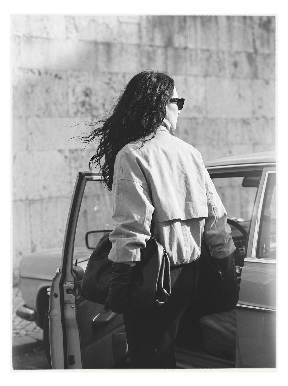 Street editorial: model stepping into a vintage car, viewed from behind