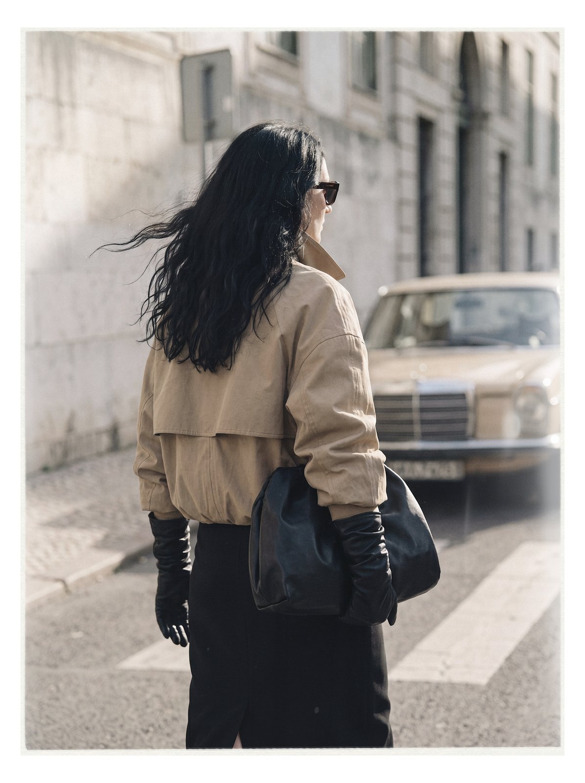 Street editorial: back view with a leather bag and a car behind